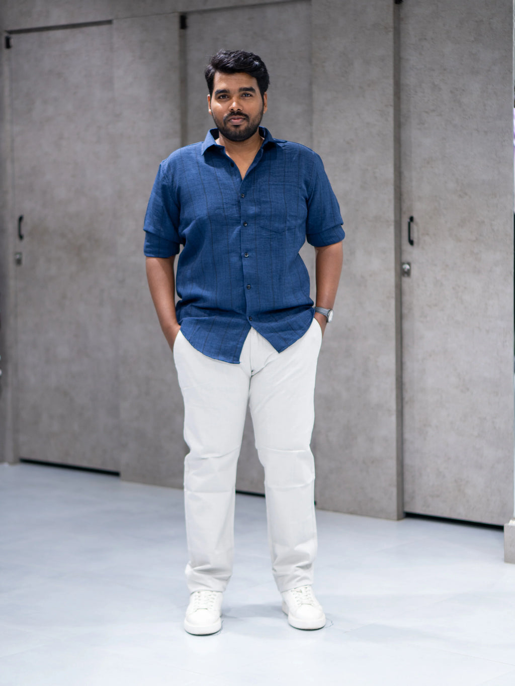 Man in navy blue short-sleeve shirt and white pants, modern casual office wear for everyday style