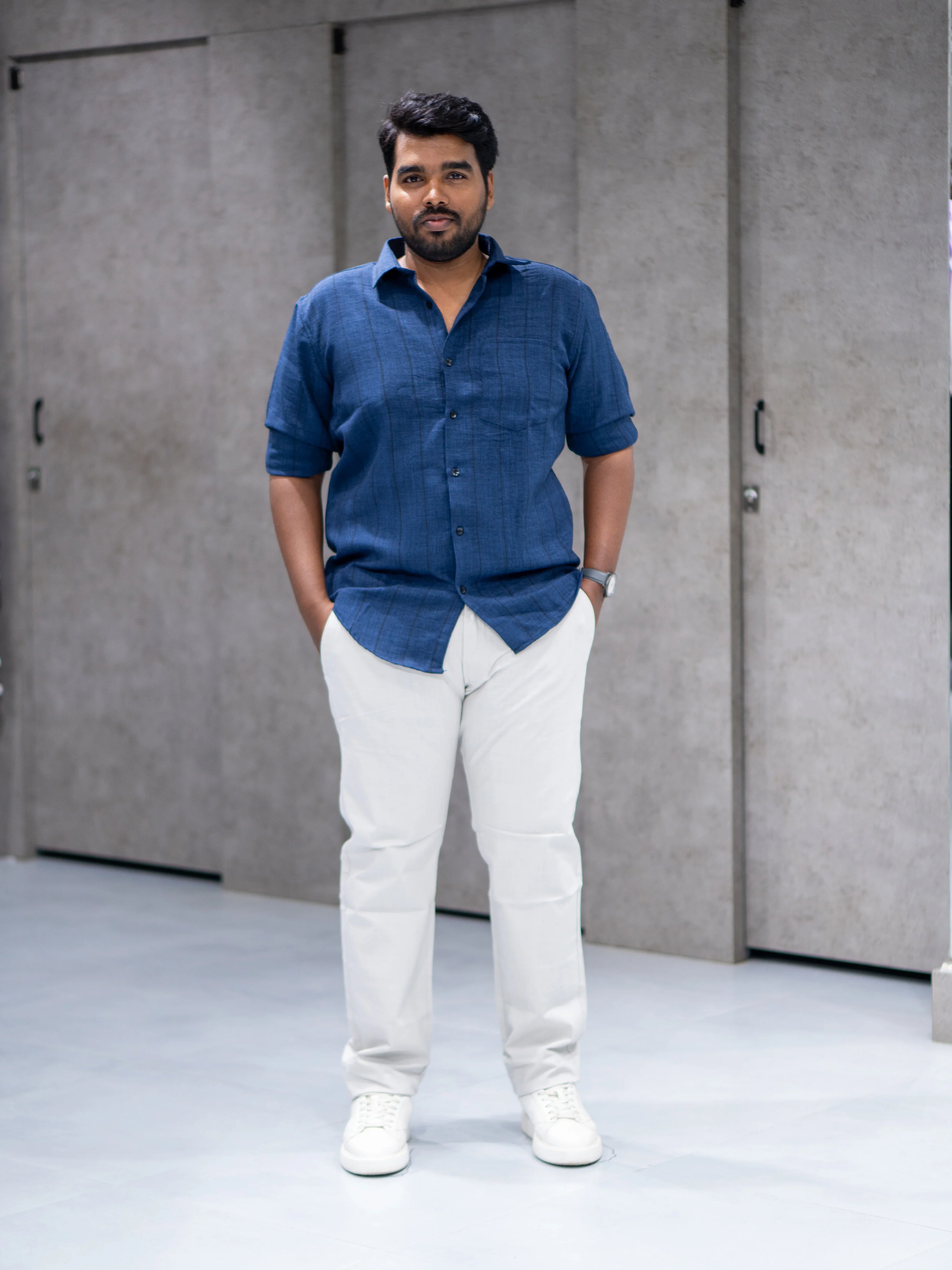 Man in navy blue short-sleeve shirt and white pants, modern casual office wear for everyday style