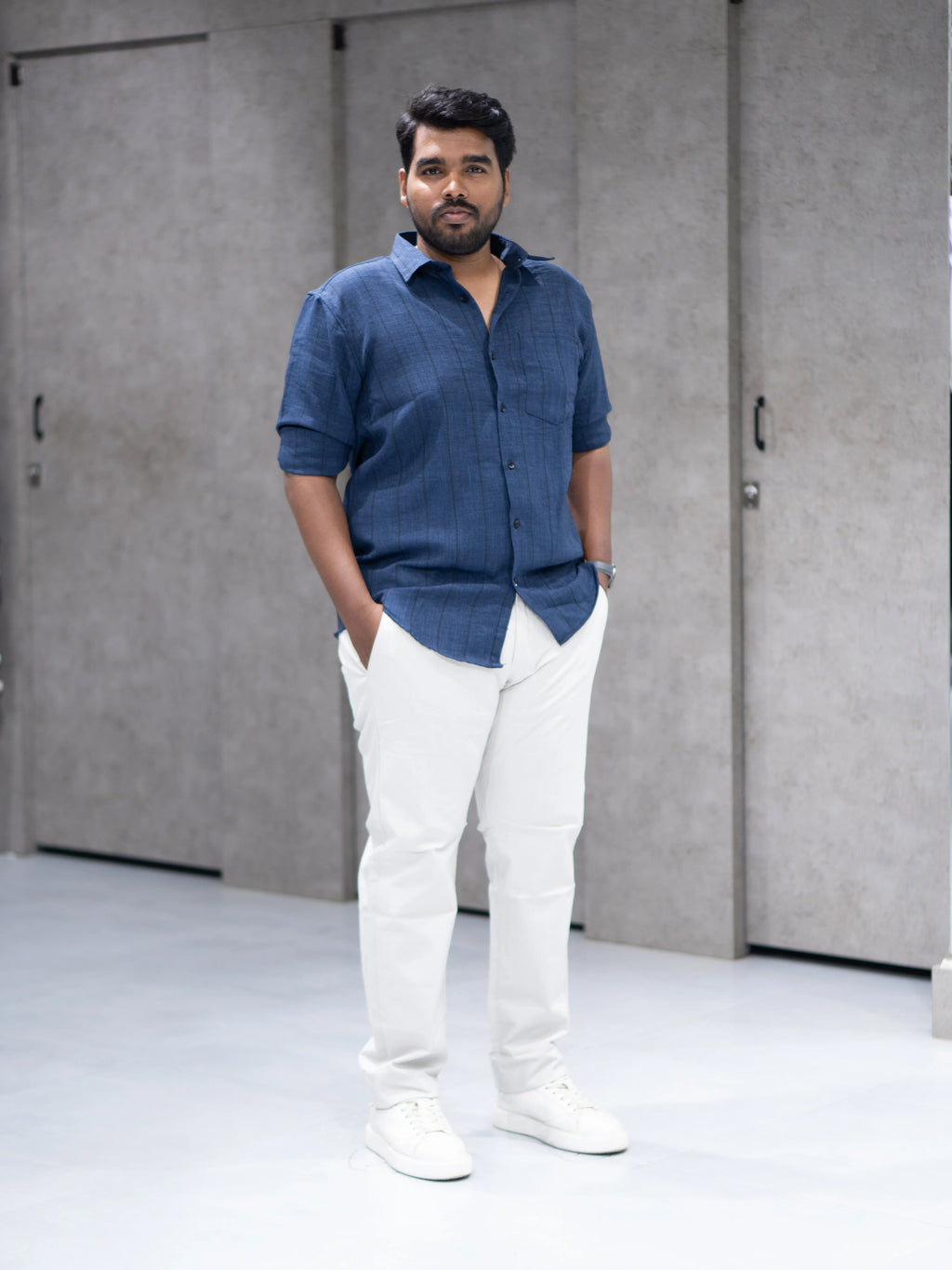 Man in navy blue striped shirt and white pants, modern casual office wear for everyday style