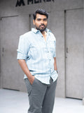 Man in light blue striped shirt and gray trousers, modern office style for everyday wear