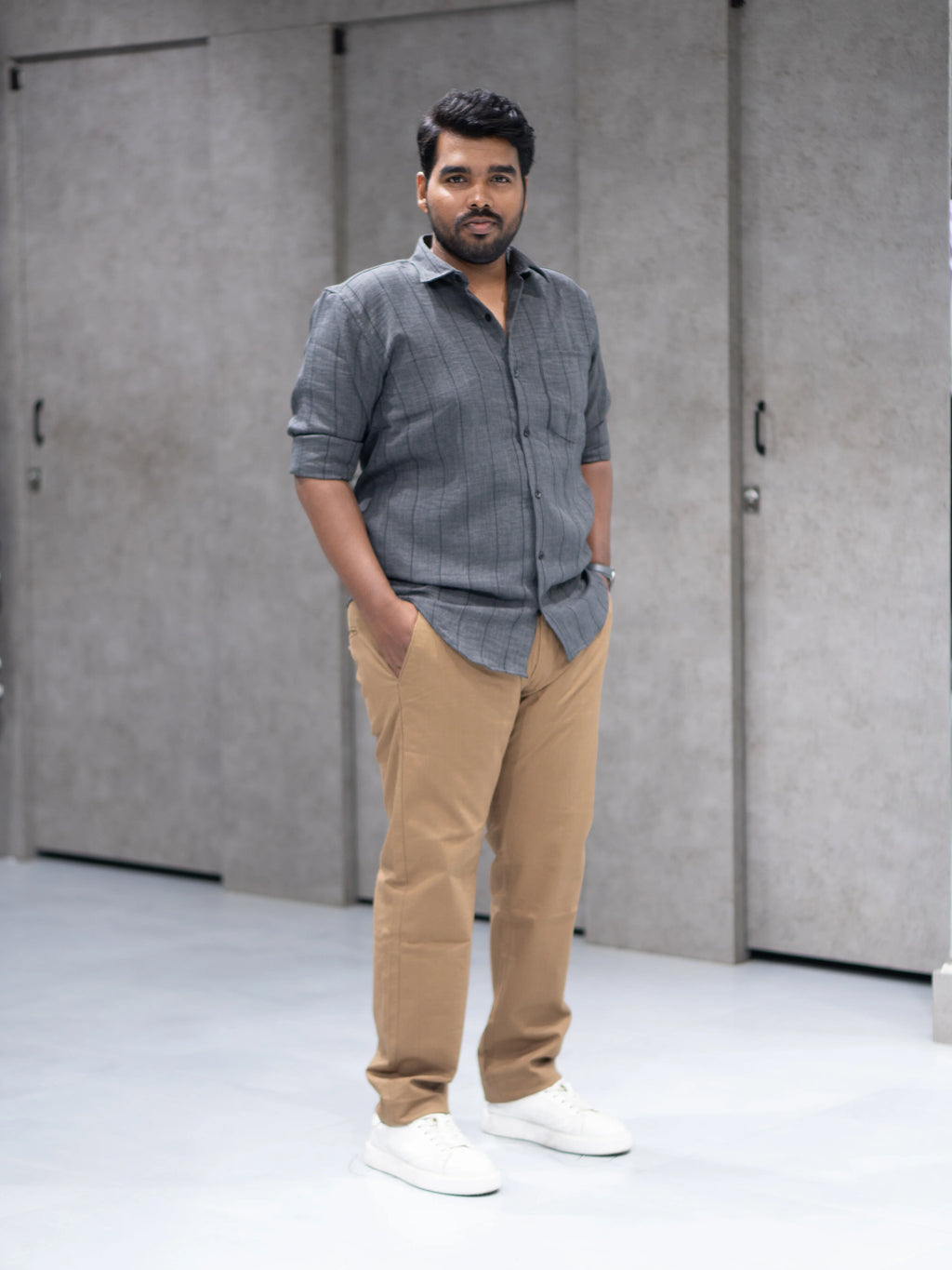 Man in gray striped shirt and beige pants, styled for modern formalwear