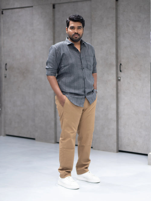 Man in gray striped shirt and beige pants, styled for modern formalwear
