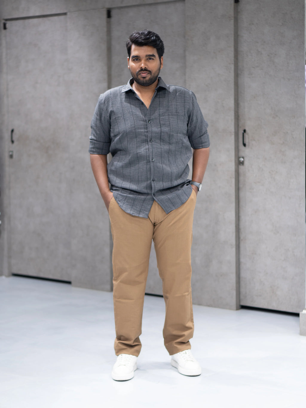 Man in gray striped shirt and beige pants, styled for modern formalwear