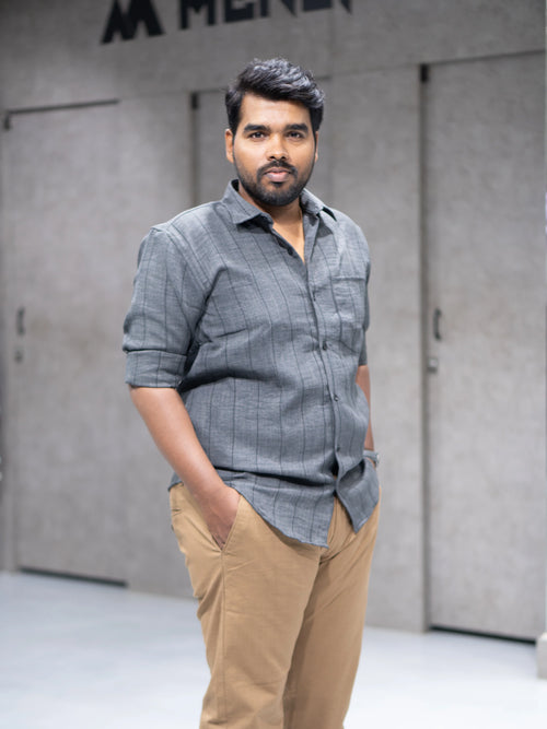 Man in gray striped button-down shirt and beige pants, modern office style