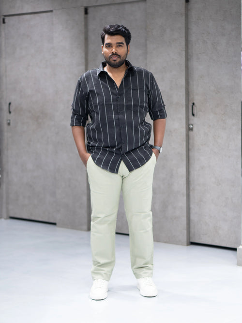 Man wearing striped black shirt and light green pants for modern formalwear style